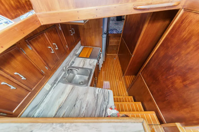 Slide: The Image of 1984 Post 43 yacht interior with wooden cabinets, marble countertop, and stainless steel sink. - 49