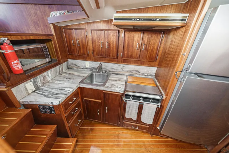 Slide: The Image of Compact wooden boat kitchen with marble countertops, stainless steel sink, and modern appliances. - 51