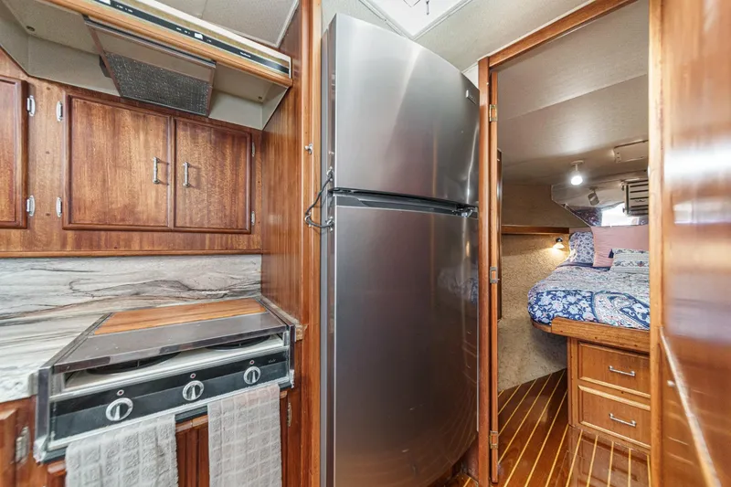 Slide: The Image of Compact boat kitchen with stainless steel fridge, wooden cabinets, and cozy sleeping area. - 53