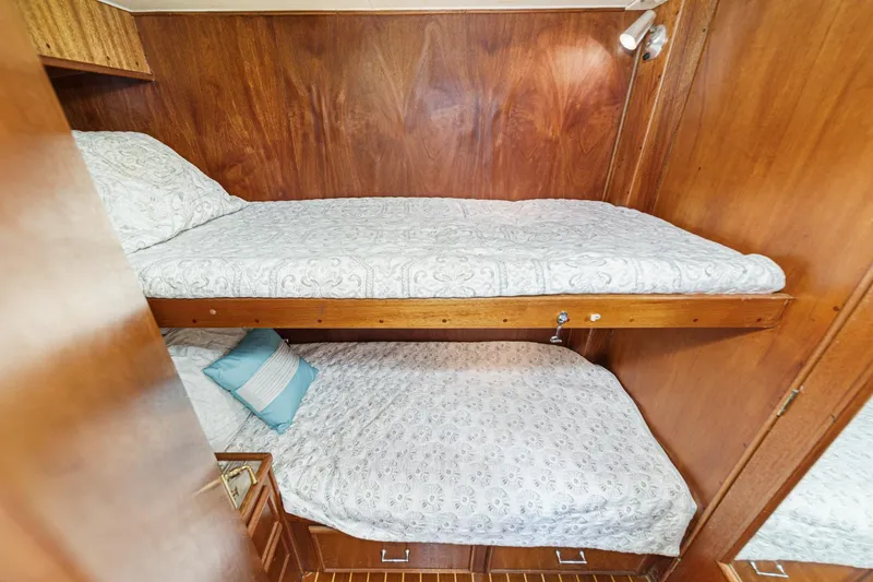Slide: The Image of Bunk beds in a 1984 Post 43 yacht cabin with wood paneling and patterned bedding. - 62