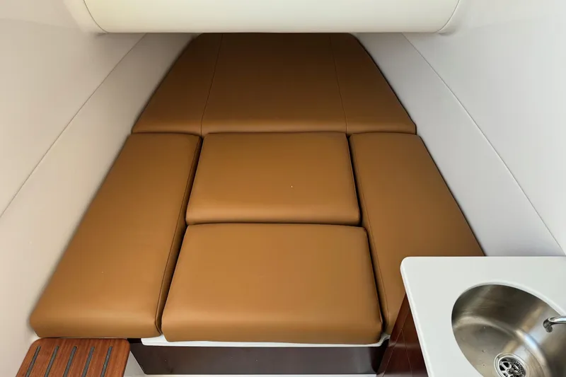 Slide: The Image of 2025 Robalo R360 Center Console cabin with brown cushions and a small sink. - 30