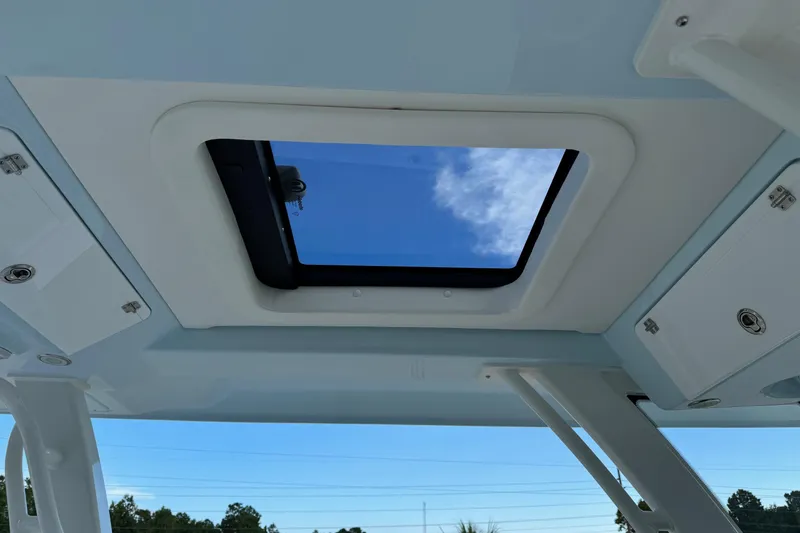Slide: The Image of 2025 Robalo R360 Center Console boat with open sunroof, showcasing clear blue sky. - 7
