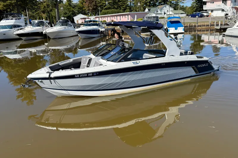 The Image of 2021 Cobalt R6 Surf boat on calm water, surrounded by other docked boats. - 0