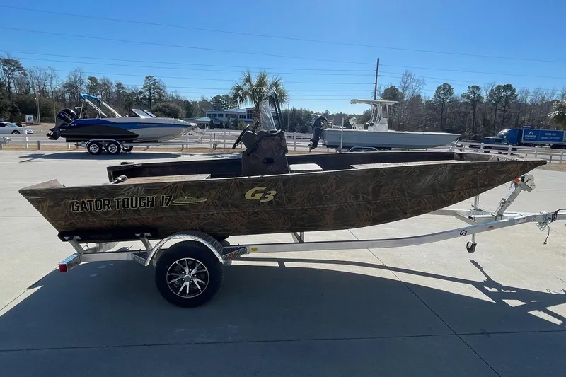 Slide: The Image of 2026 G3 17 CC Shadow Grass boat on trailer, camo design, parked outdoors. - 6