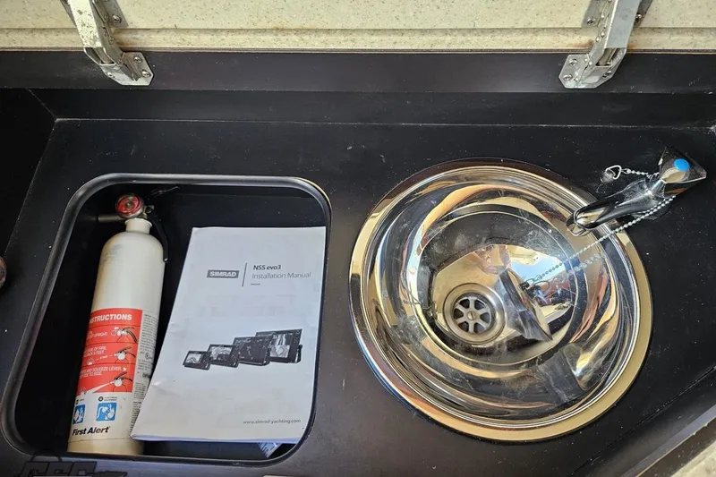 Slide: The Image of Fire extinguisher, manual, and sink in 2007 Fountain 35 Lightning boat interior. - 81