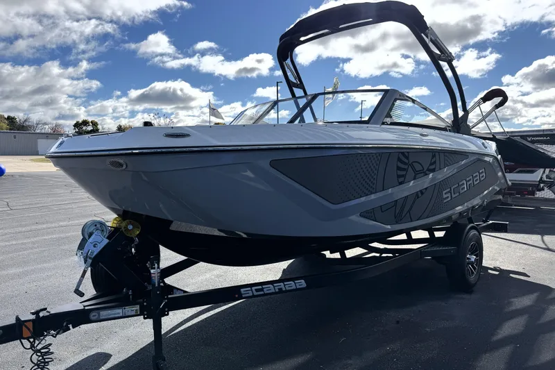 Slide: The Image of 2026 Scarab 210 LX boat on trailer under cloudy sky. - 2