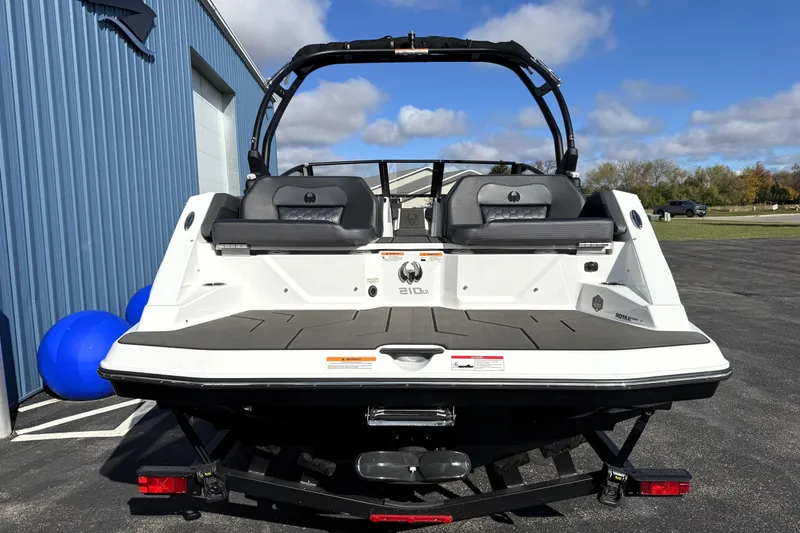 Slide: The Image of 2026 Scarab 210 LX boat rear view, parked outdoors on a sunny day. - 5