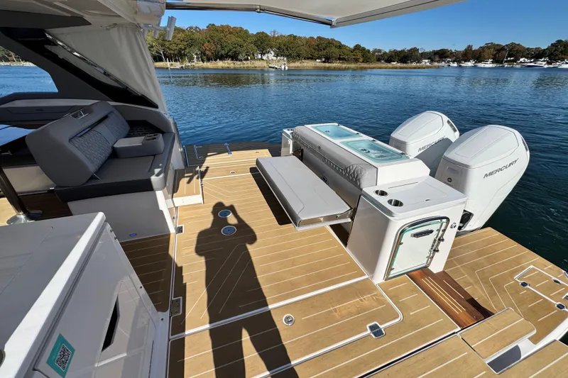 Slide: The Image of Luxury Regal LX43 2025 boat deck with seating, storage, and Mercury engines on a serene lake. - 15