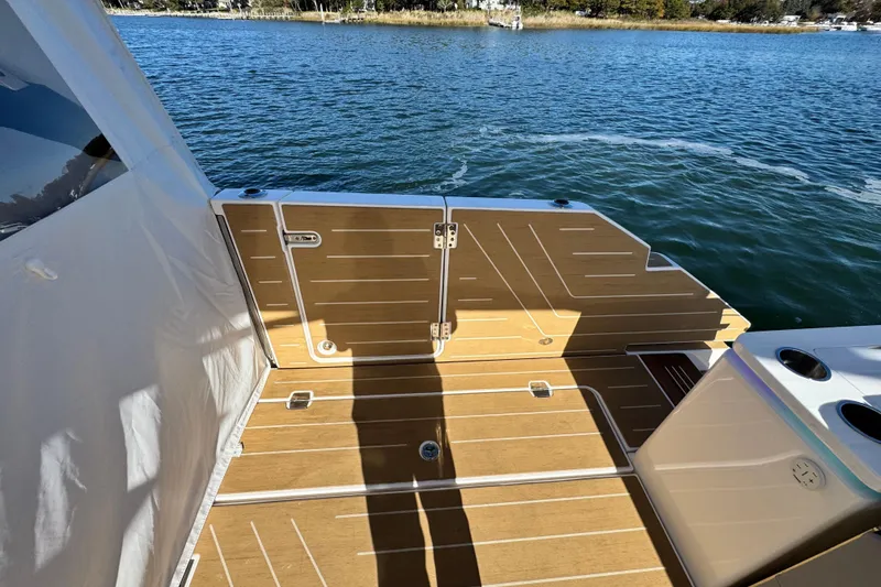 Slide: The Image of 2025 Regal LX43 boat deck with wooden flooring, overlooking serene water. - 27