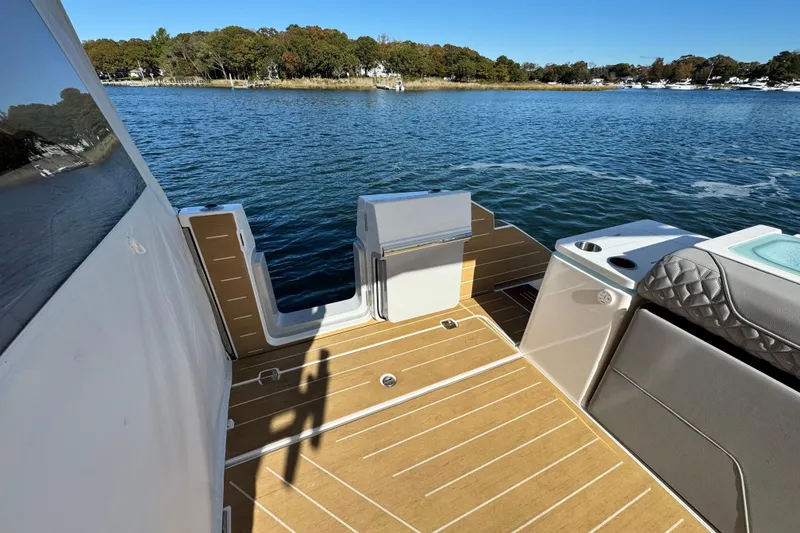Slide: The Image of 2025 Regal LX43 boat deck with seating, overlooking serene water and lush shoreline. - 28