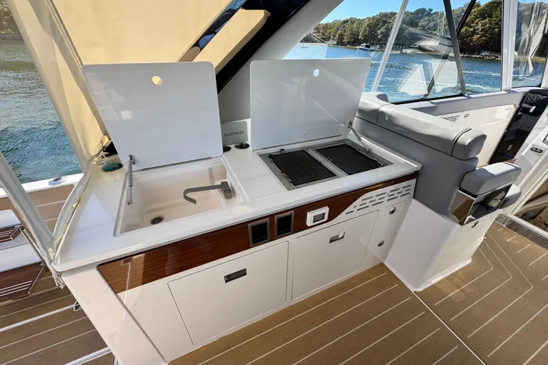 Slide: The Image of Luxury yacht kitchen area on 2025 Regal LX43, featuring sink and grill with scenic water view. - 31