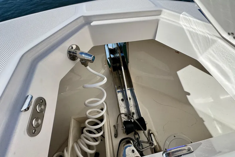 Slide: The Image of Anchor compartment of 2025 Regal LX43 boat with coiled hose and fittings. - 55