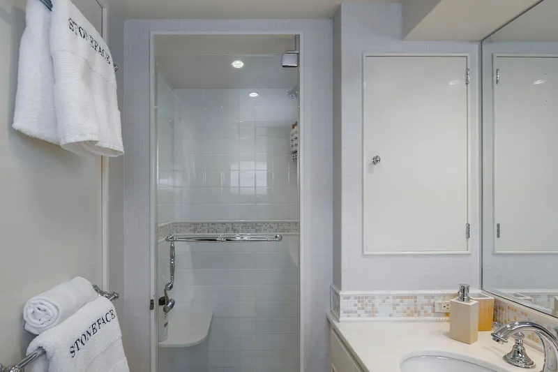 Slide: The Image of Modern bathroom with white tiles, shower, and elegant fixtures, featuring "Stoneface" branded towels. - 30