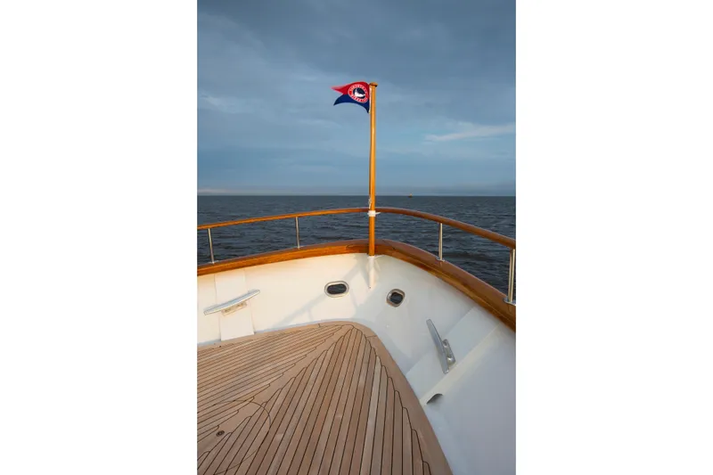 Slide: The Image of Bow of 1978 Burger Custom yacht with flag, overlooking calm sea and cloudy sky. - 35