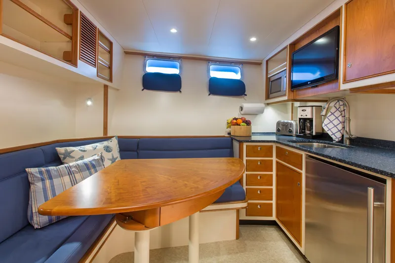 Slide: The Image of Cozy 1978 Burger Custom yacht interior with kitchen and dining area, featuring blue seating and wooden accents. - 43