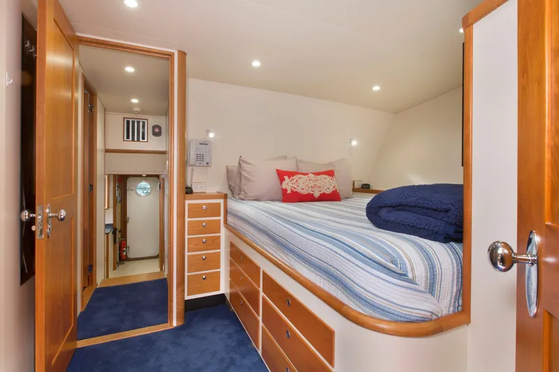 Slide: The Image of Cozy bedroom interior on a 1978 custom Burger yacht with striped bedding and wooden cabinetry. - 44