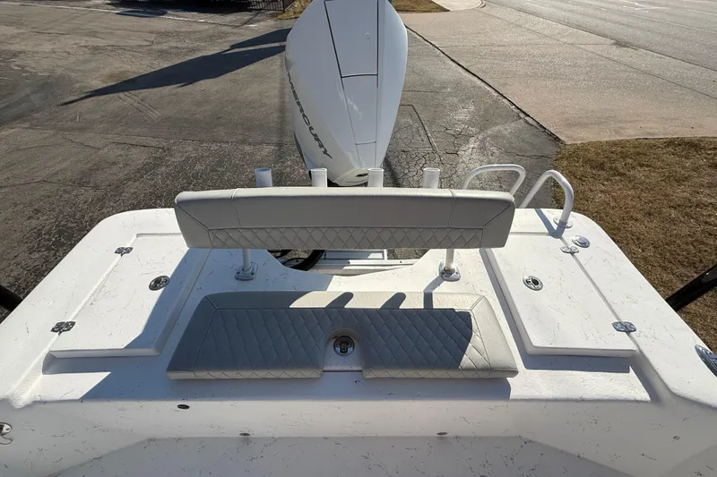 Slide: The Image of 2026 Blazer Bay 2400 boat with cushioned seating and Mercury engine, parked on pavement. - 14