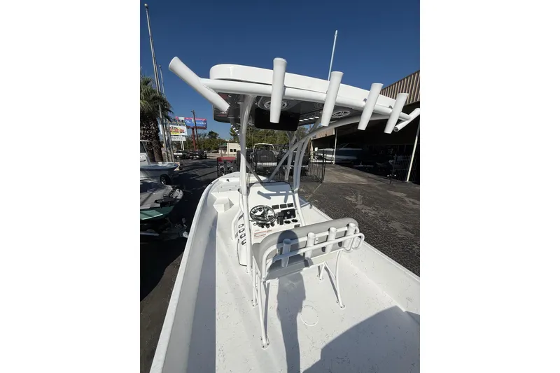 Slide: The Image of 2026 Blazer Bay 2400 boat with T-top and rod holders, parked outdoors. - 15