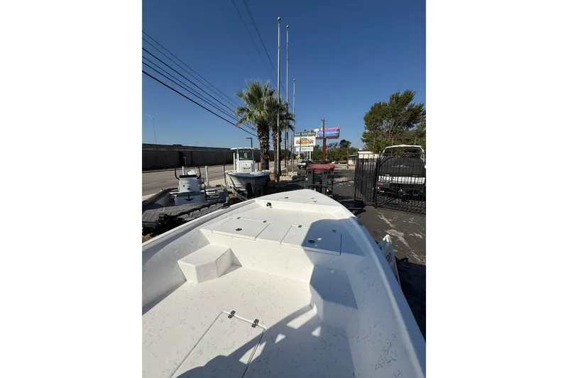 Slide: The Image of 2026 Blazer Bay 2400 boat on display outdoors, surrounded by palm trees and other boats. - 33