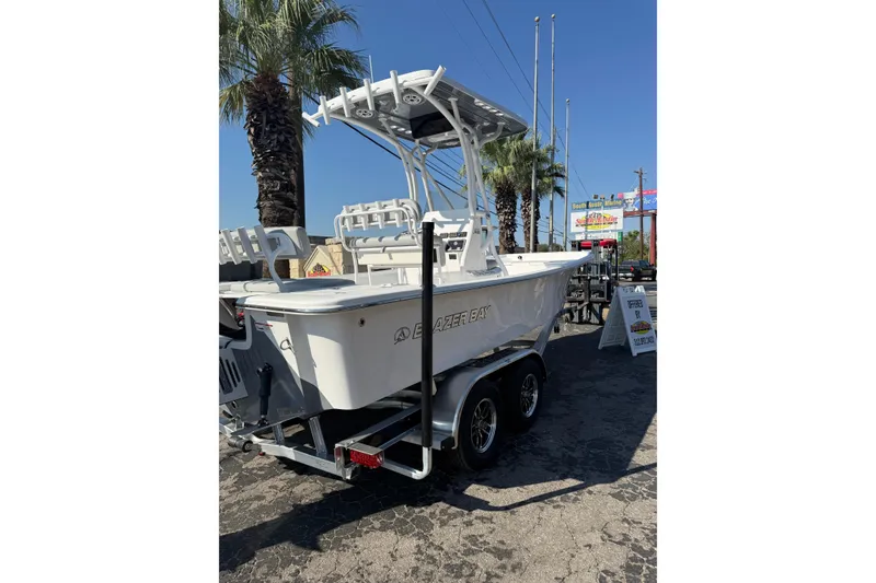 Slide: The Image of 2026 Blazer Bay 2400 boat on trailer, displayed outdoors under clear blue sky. - 39