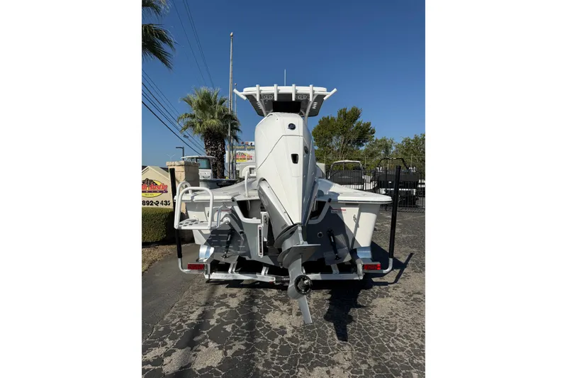 Slide: The Image of 2026 Blazer Bay 2400 boat, rear view, parked on a trailer under clear blue sky. - 5