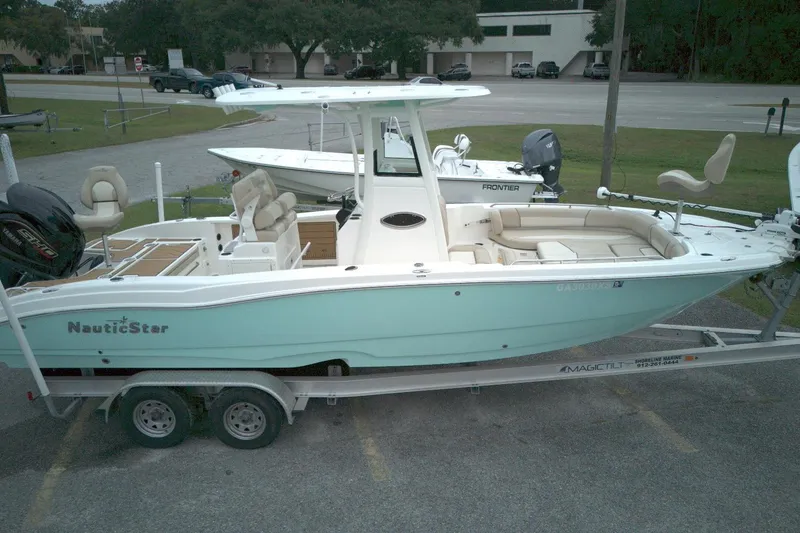 The Image of 2022 NauticStar 251 Hybrid boat on trailer, light blue hull, parked outdoors. - 0