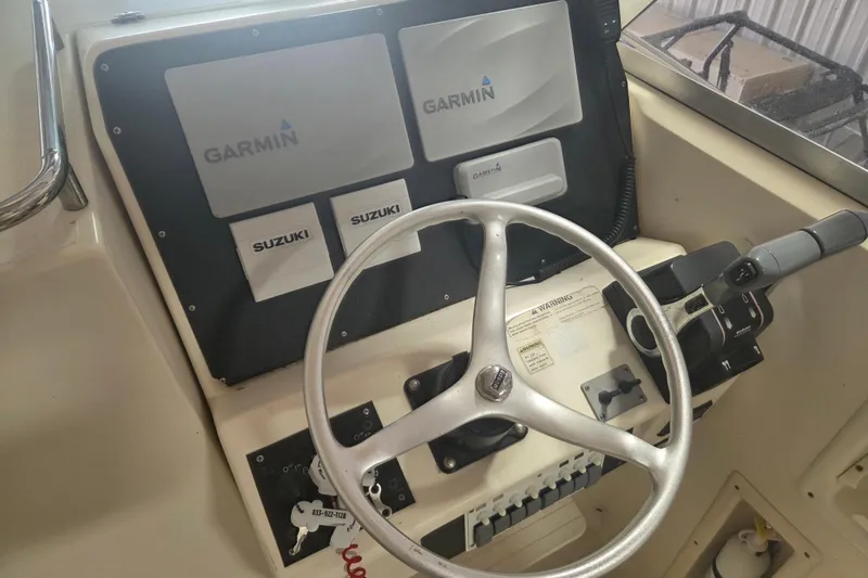 Slide: The Image of 2001 Pursuit 2870 Walkaround boat dashboard with Garmin and Suzuki controls. - 12