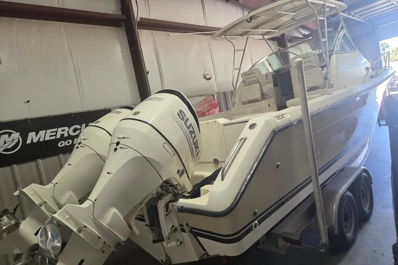 Slide: The Image of 2001 Pursuit 2870 Walkaround boat with dual Suzuki outboard motors in a garage. - 2