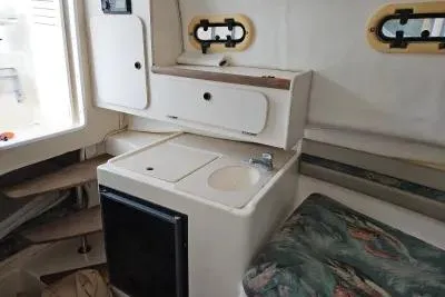 Slide: The Image of 2001 Pursuit 2870 Walkaround boat interior with compact kitchenette and seating area. - 7