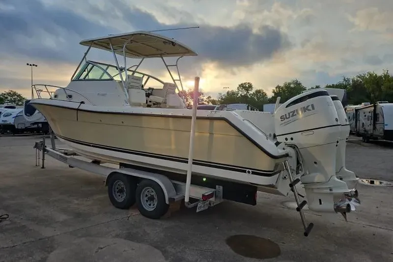 Slide: The Image of 2001 Pursuit 2870 Walkaround boat on trailer at sunset, featuring Suzuki outboard motor. - 8