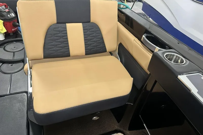 Slide: The Image of 2021 MasterCraft X26 interior with tan and black seating, cup holder, and storage compartment. - 4