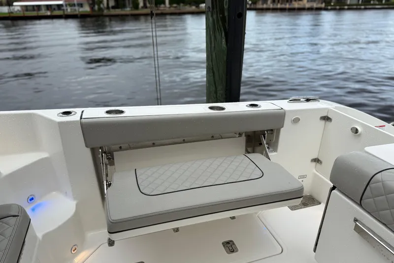 Slide: The Image of 2025 Pursuit OS 325 Offshore boat with foldable seating and cup holders by the water. - 16