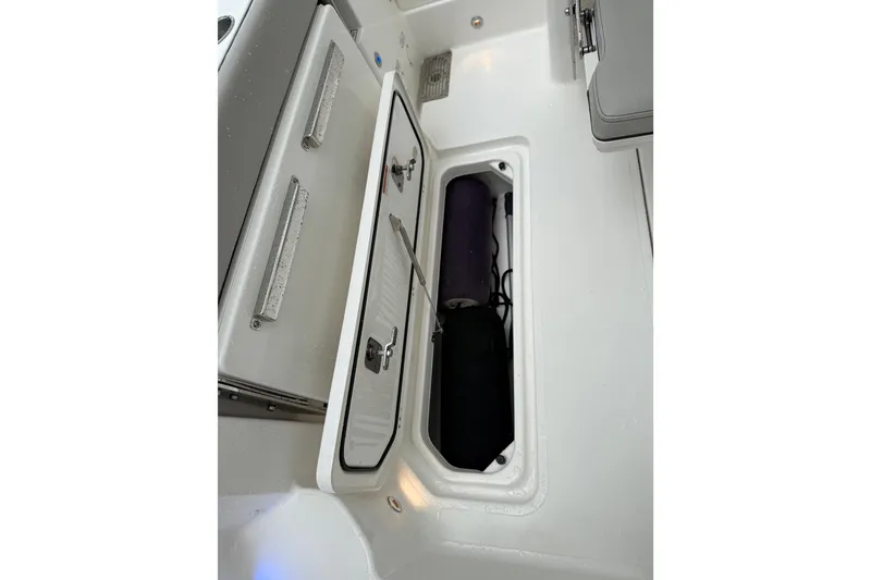 Slide: The Image of 2025 Pursuit OS 325 Offshore boat storage compartment with open hatch and visible equipment. - 21