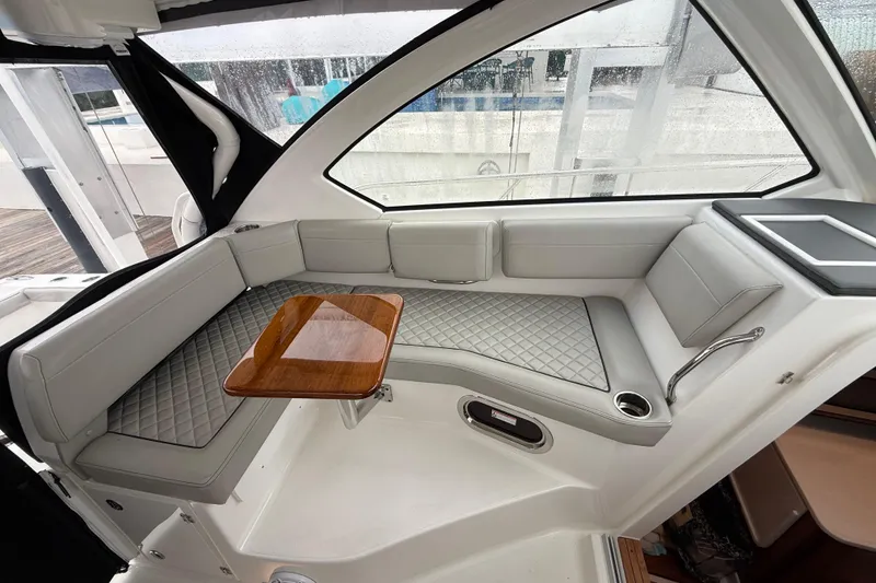 Slide: The Image of 2025 Pursuit OS 325 Offshore boat interior with cushioned seating and wooden table. - 31