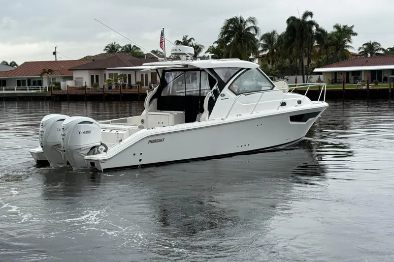 Slide: The Image of 2025 Pursuit OS 325 Offshore boat on calm water, surrounded by waterfront homes. - 4