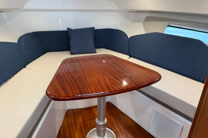 Slide: The Image of 2025 Pursuit OS 325 Offshore cabin with wooden table and blue seating. - 54