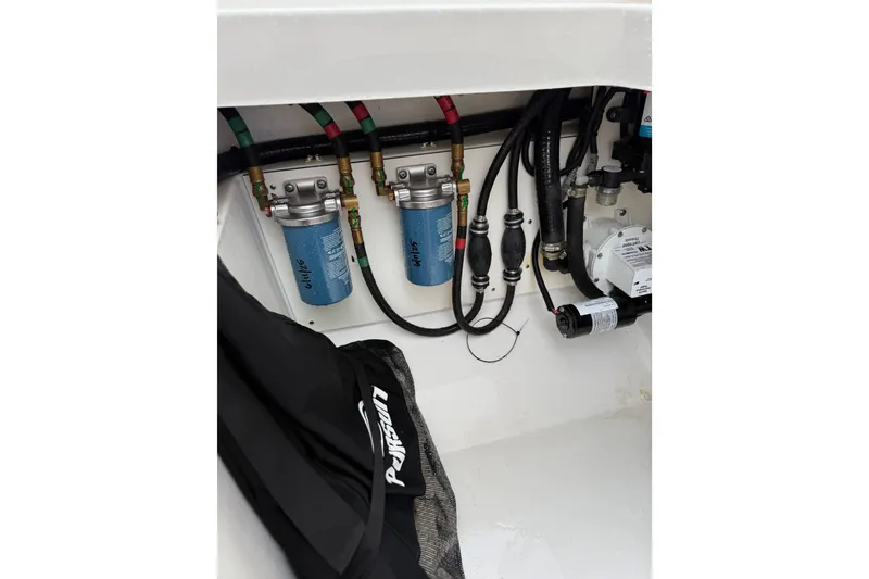 Slide: The Image of 2025 Pursuit OS 325 Offshore engine compartment with filters and hoses. - 79