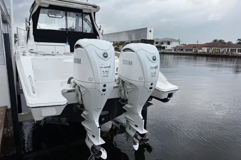 Slide: The Image of 2025 Pursuit OS 325 Offshore boat with twin Yamaha 350 V8 engines docked by waterfront homes. - 8