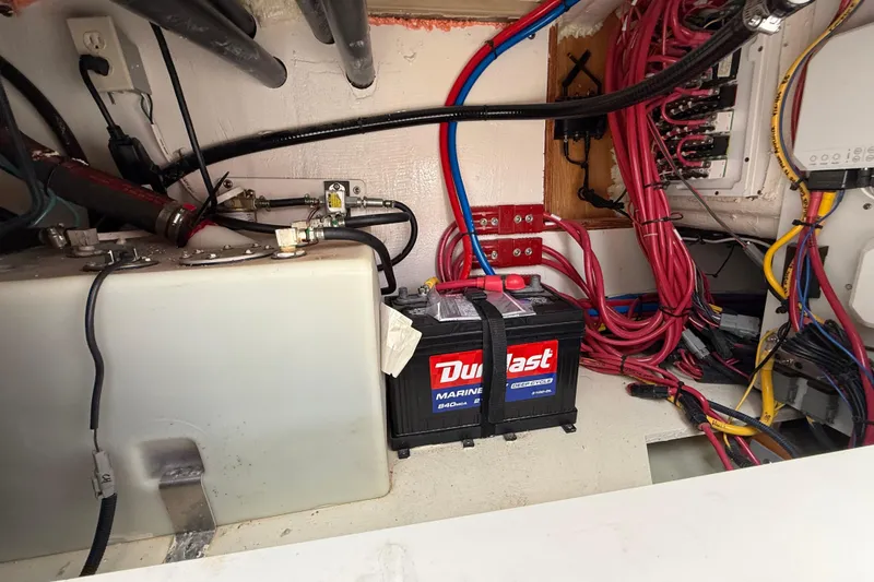 Slide: The Image of 2025 Pursuit OS 325 Offshore boat battery compartment with wiring and marine battery. - 80