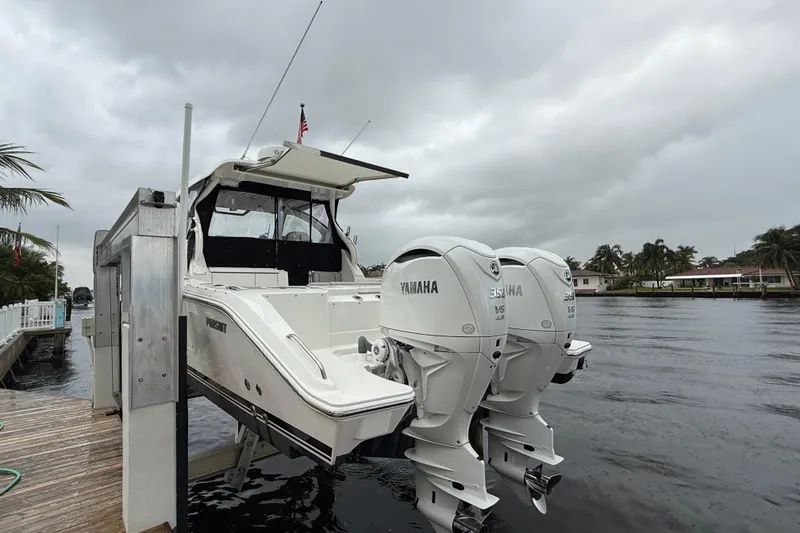 Slide: The Image of 2025 Pursuit OS 325 Offshore boat with twin Yamaha engines docked by a waterfront. - 9