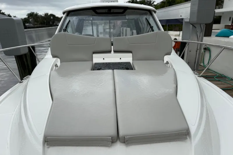 Slide: The Image of 2025 Pursuit OS 325 Offshore boat with cushioned deck seating, docked by the water. - 90