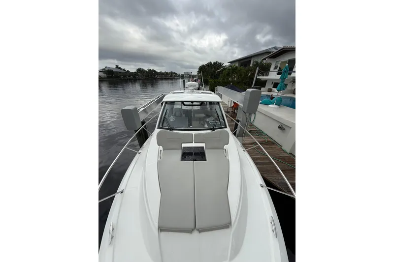 Slide: The Image of 2025 Pursuit OS 325 Offshore boat docked by a waterfront home under cloudy skies. - 91
