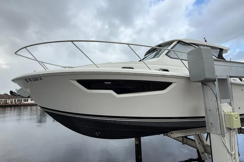 Slide: The Image of 2025 Pursuit OS 325 Offshore boat on lift, cloudy sky background. - 95