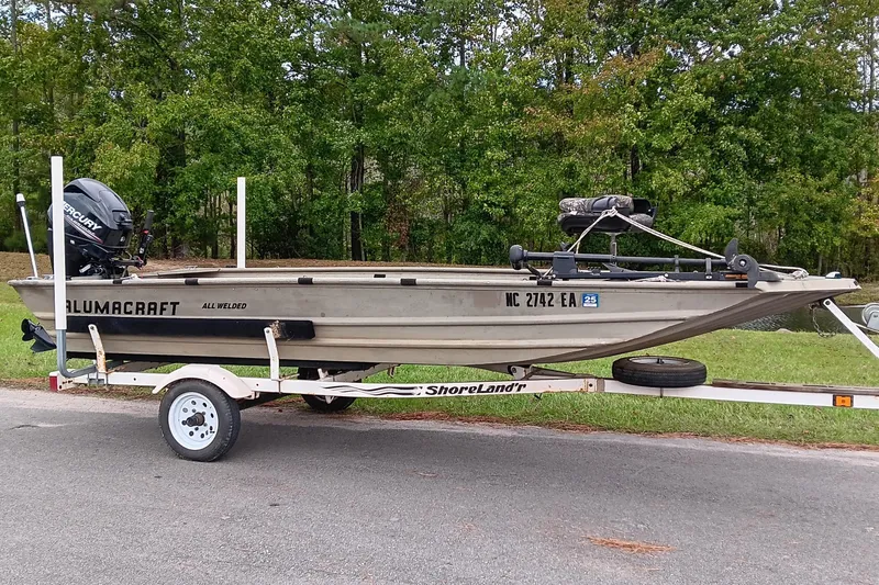 Slide: The Image of 2006 Alumacraft Crappie Jon boat on trailer, parked outdoors with trees in background. - 0