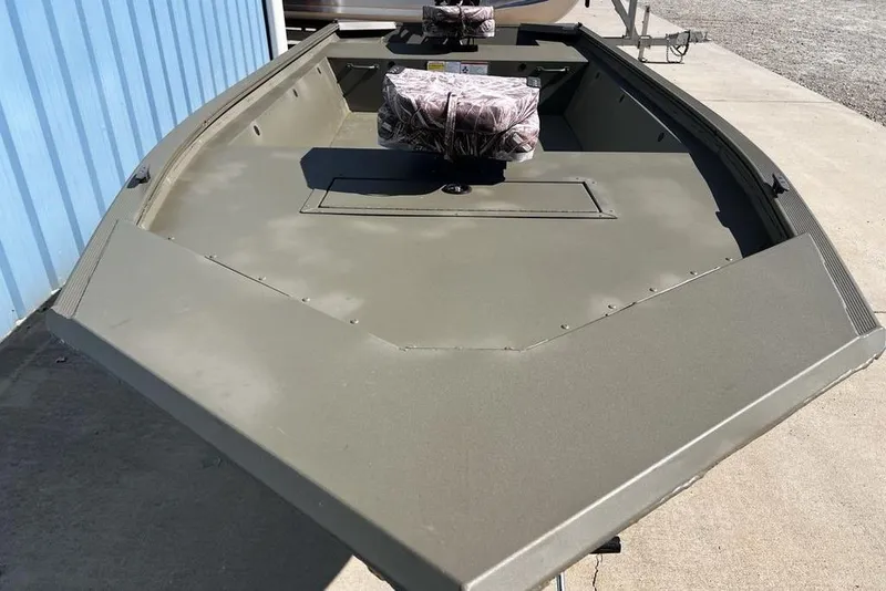 Slide: The Image of 2025 Tracker Grizzly 1648 Utility boat with camo seats, parked on concrete. - 10