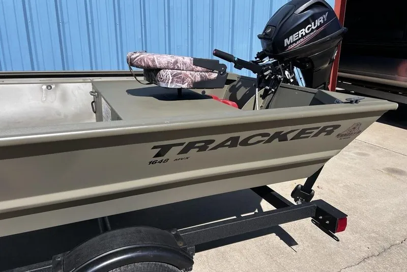 Slide: The Image of 2025 Tracker Grizzly 1648 Utility boat with Mercury engine, parked outdoors. - 12