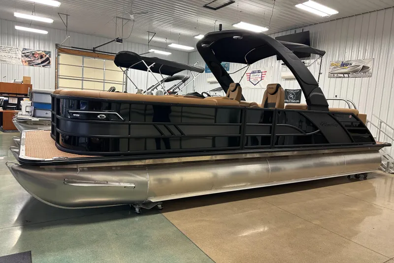 Slide: The Image of 2025 Bentley Pontoons Elite 253 Admiral in showroom, sleek black design, luxury seating. - 9