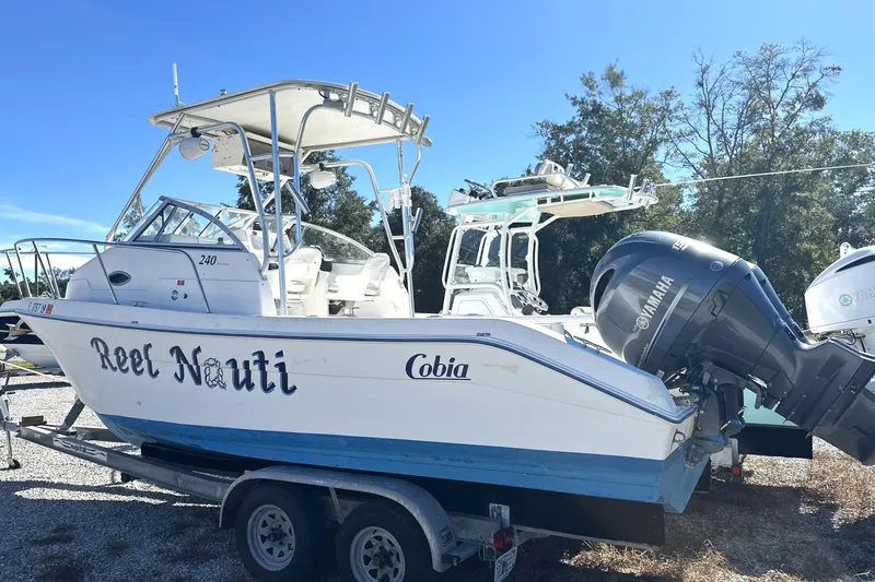 Slide: The Image of 2000 Cobia 240 Walkaround boat on trailer with Yamaha outboard motor, named "Reel Nauti." - 1