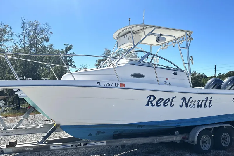Slide: The Image of 2000 Cobia 240 Walkaround boat named "Reel Nauti" on a trailer, sunny day. - 18