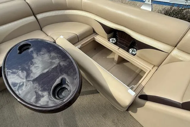 Slide: The Image of 2014 Harris FloteBote Sunliner 200 interior with beige seating, storage compartment, and round table. - 16